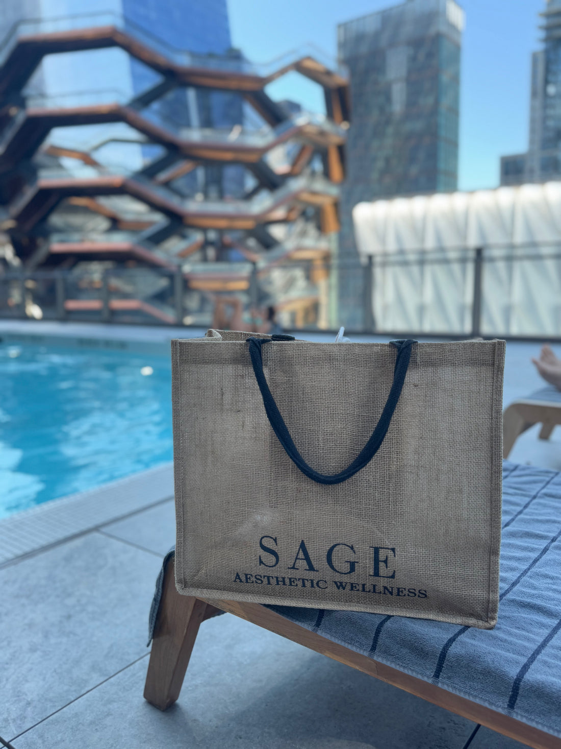 Sage Aesthetic Wellness tote bag by rooftop pool with Vessel NYC in background, featured for Scottsdale med spa lifestyle branding