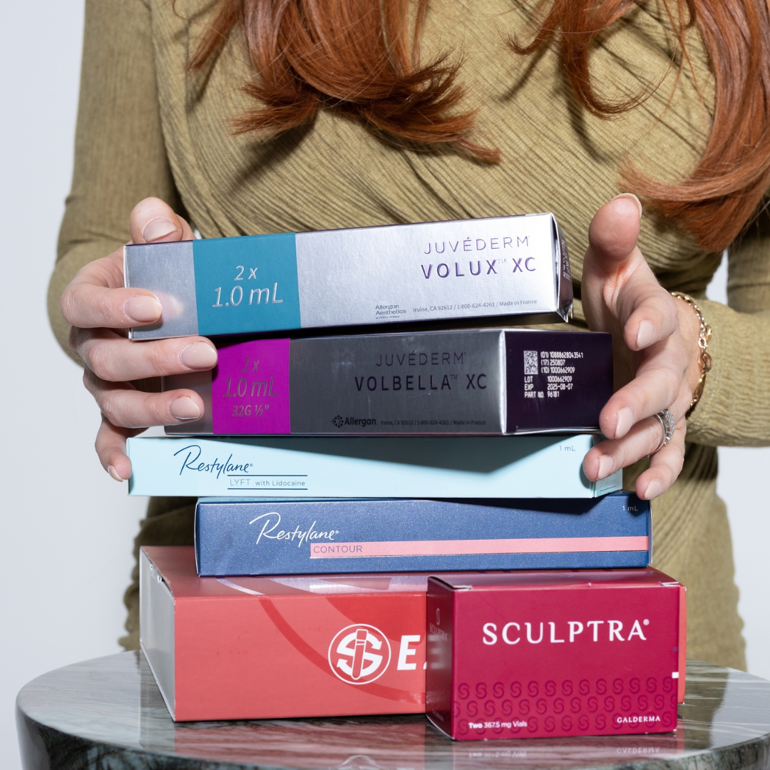 Hands holding Juvederm, Restylane, and Sculptra injectable product boxes at Sage Aesthetic Wellness in Scottsdale